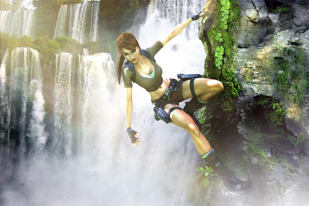 Lara in Ghana, hanging from a cliff side with a grand waterfall behind her.