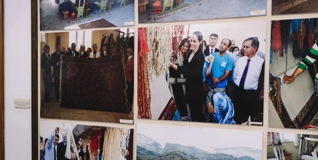 A wall displaying a series of framed photographs showing various cultural and travel scenes, with people interacting in different settings.