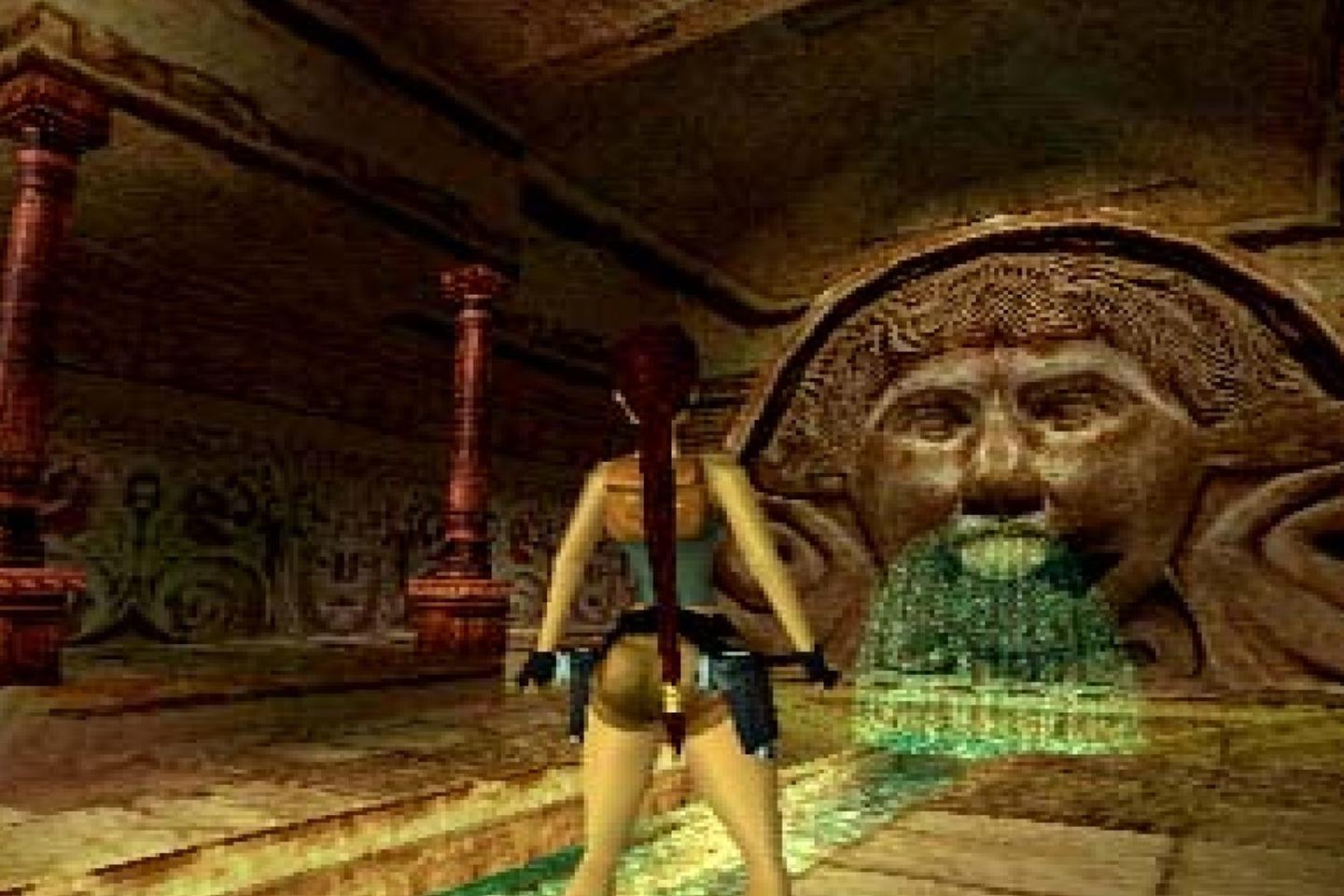 Lara facing fountain with a large face in dimly lit tomb.