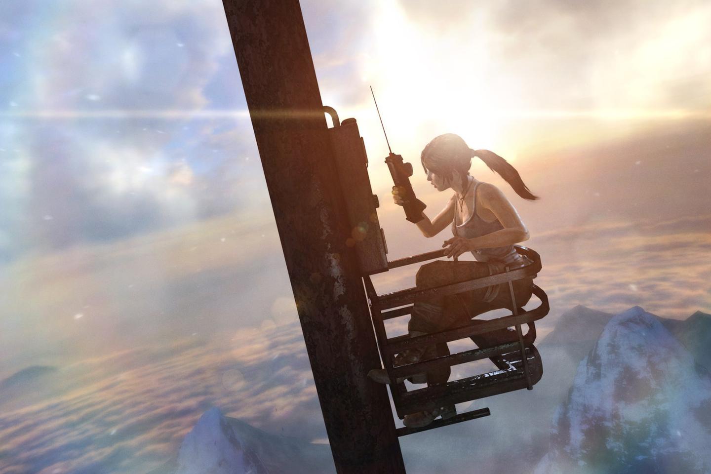 Lara holding a large phone sitting on metal contraption attached to pole high above snowy mountaintops. 