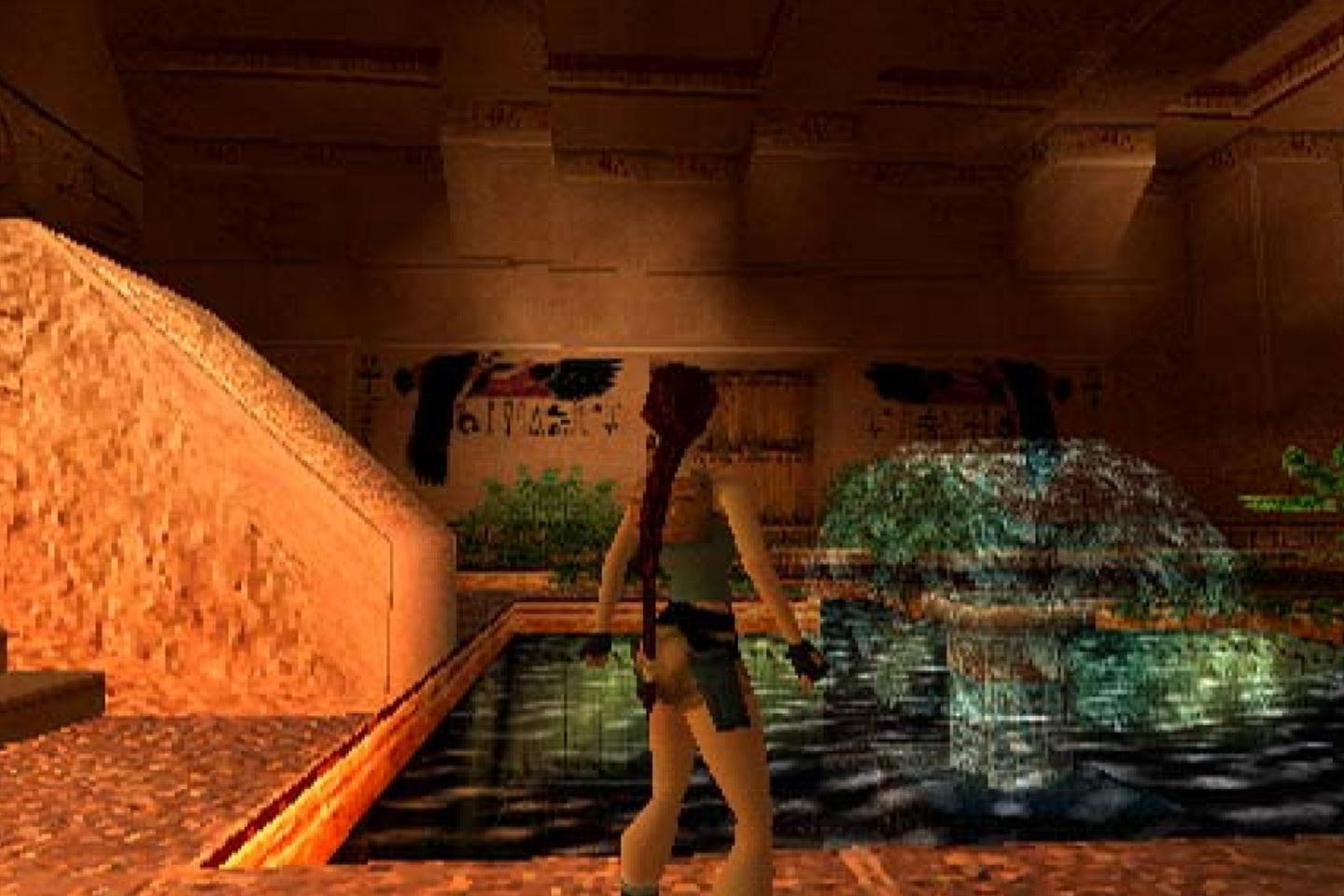 Lara walking by fountain in the middle of a dimly lit tomb.