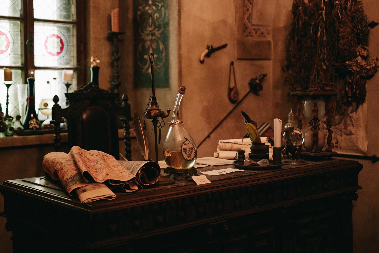 A vintage desk topped with an assortment of old-time scientific equipment, rolled parchment, and other antique items, evoking a historical study room.