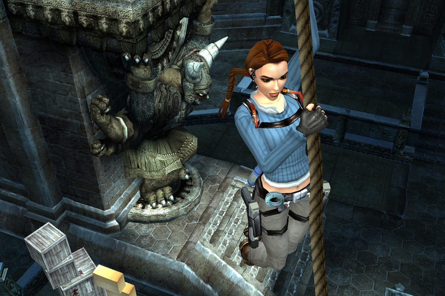 Lara holding onto rope dangling above tomb stairs.