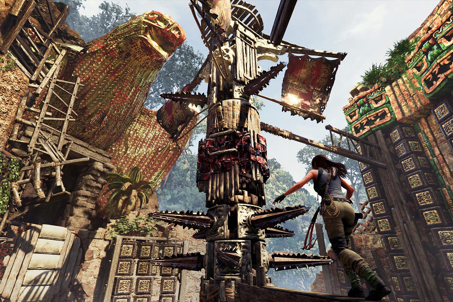 An adventurous screenshot from a Tomb Raider game depicting Lara Croft climbing an intricate wooden structure adorned with colorful tribal decorations in a dense, ruin-filled jungle setting.