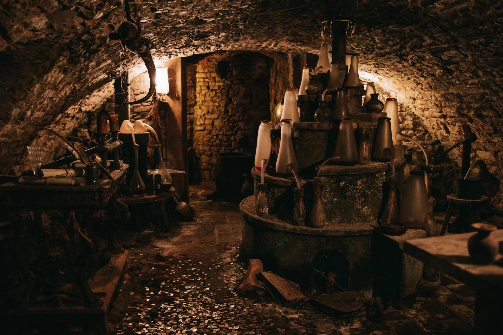 A photo inside a candlelit stone room filled with medieval equipment, creating a rustic and historical ambiance.
