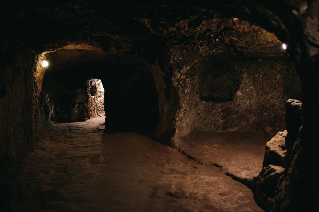 A wide tunnel inside a cave, lit at intervals, leading into the darkness with an air of quiet solitude.