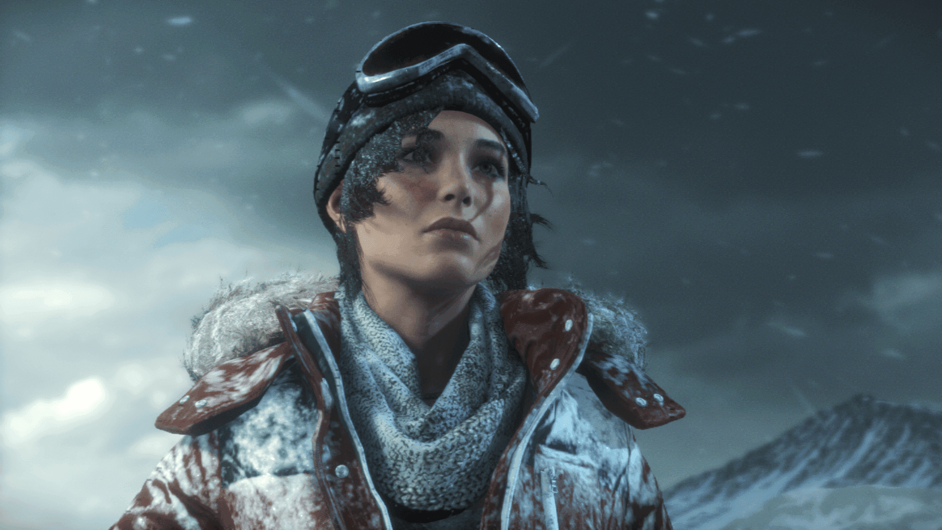 A close-up of a Lara Croft wearing a snow-covered jacket and goggles, with a snowy mountain landscape in the background.
