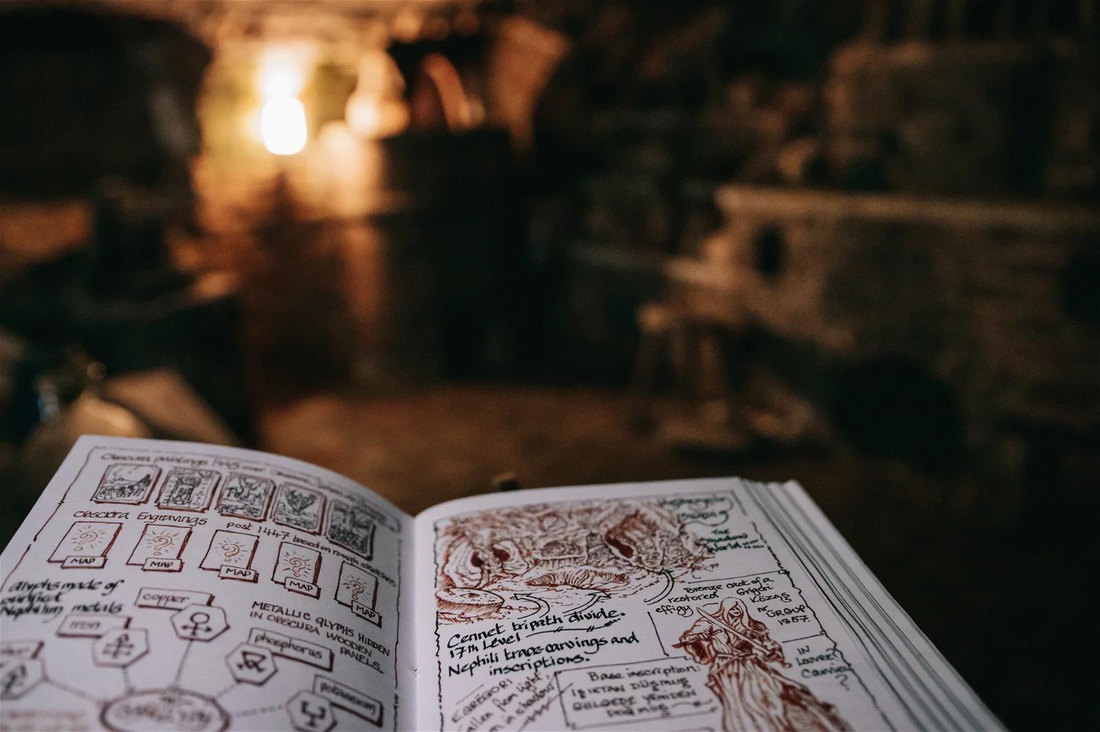 An open book with detailed sketches and notes, positioned in a softly lit, antique-looking workshop.