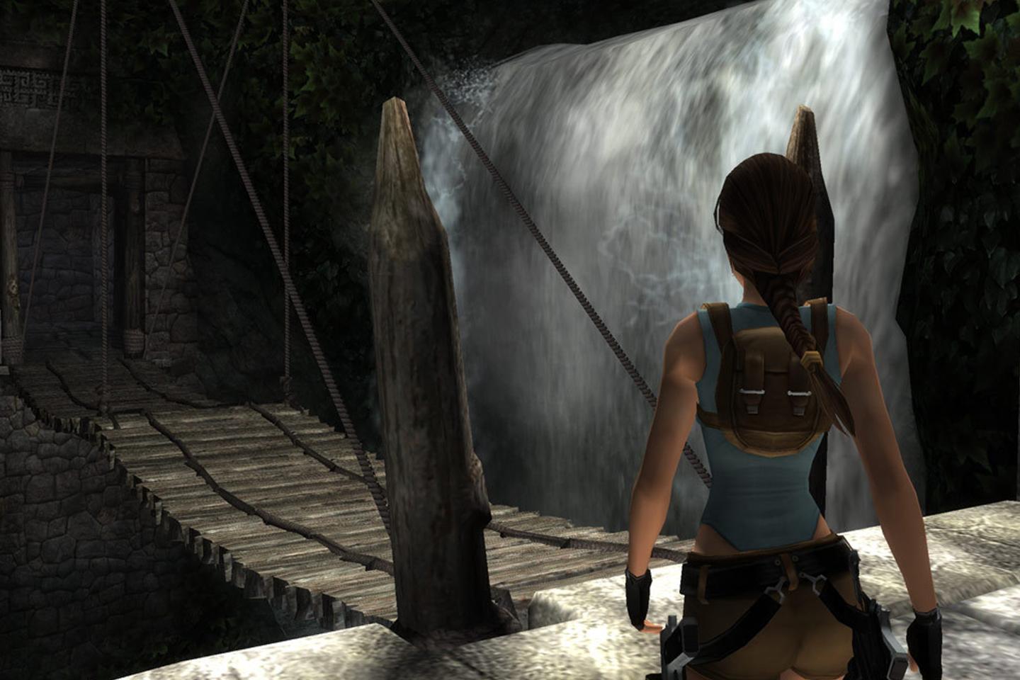 Lara facing suspension bridge near waterfall.