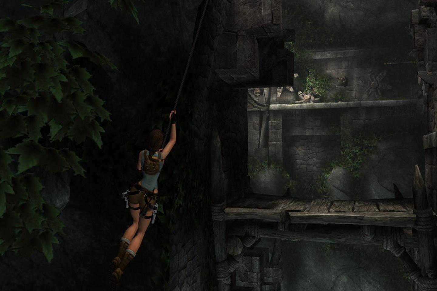 Lara swinging from rope toward ledge inside dimly-lit tomb.