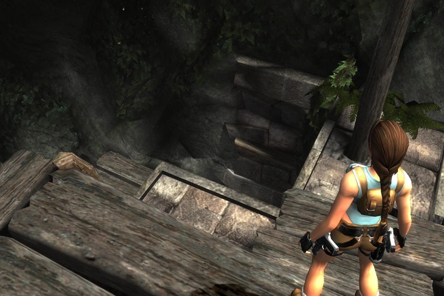 Lara looking out over dark staircase inside of stone tomb.