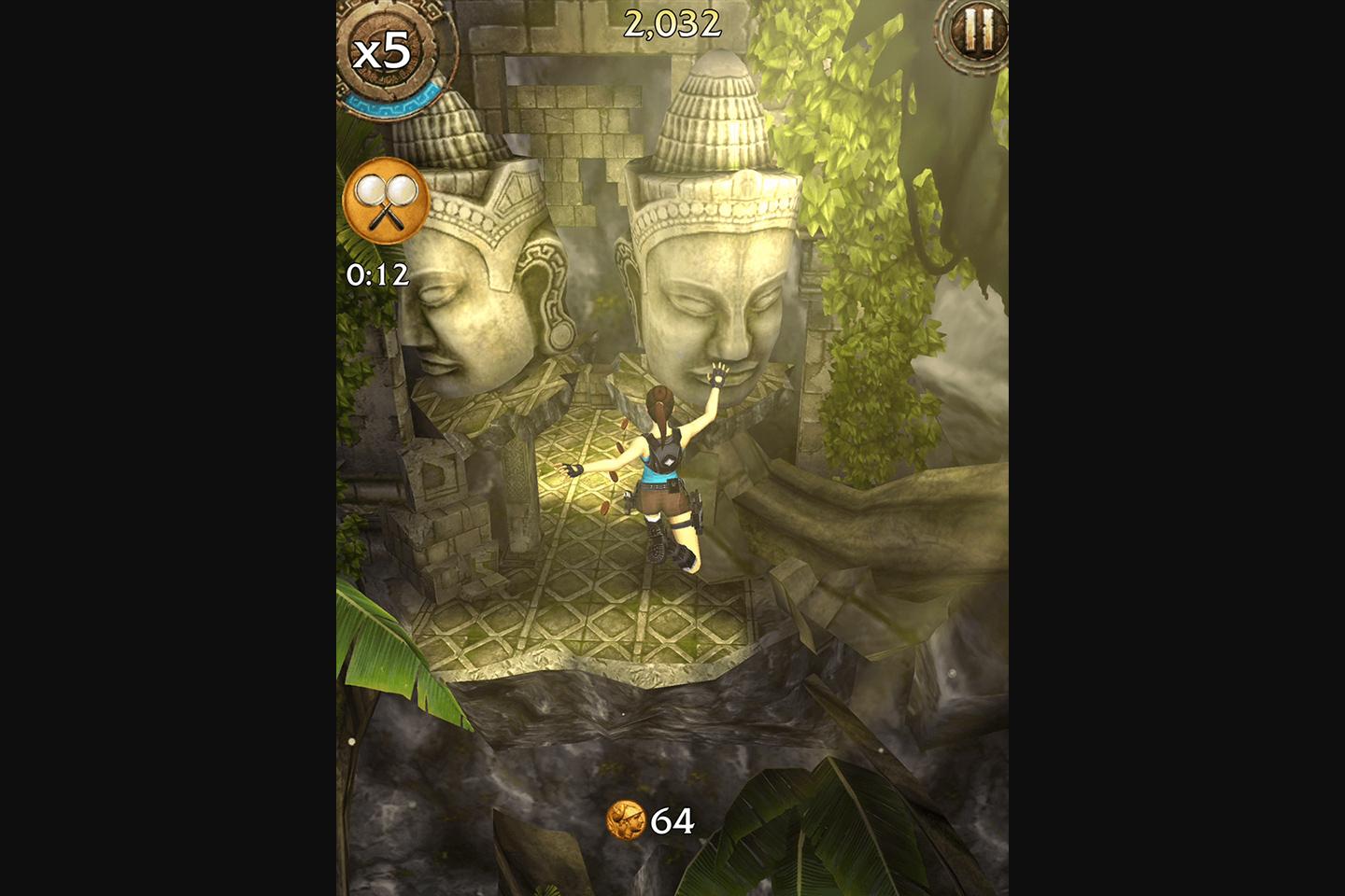 Lara Croft swinging from a rope in a jungle setting with ancient stone faces in the background, in a mobile game scene emphasizing agility and adventure.
