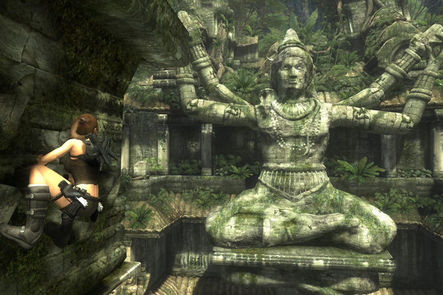 Lara climbing tomb wall near rock sculpture of a four-armed god.