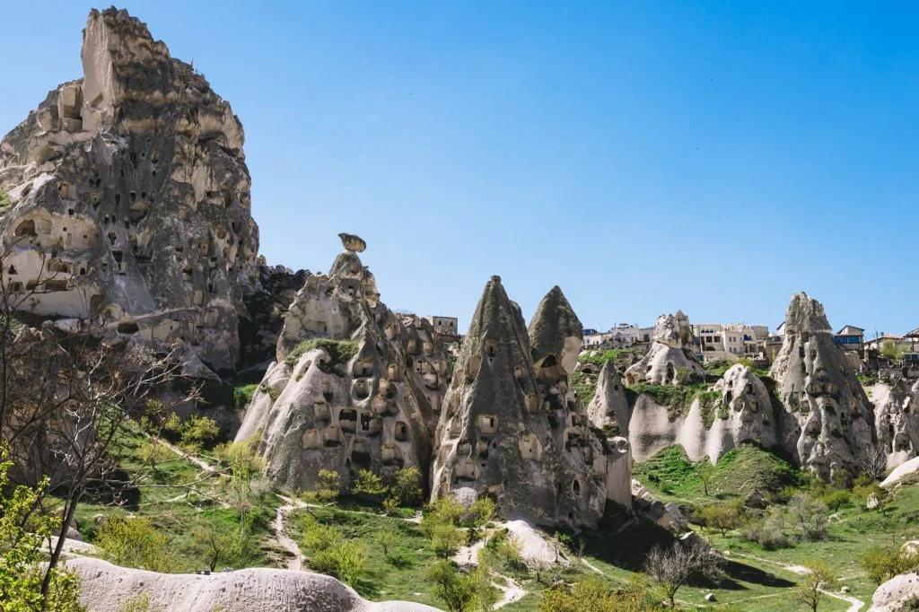 A scenic landscape of a hillside town with houses interspersed among tall, conical rock formations.