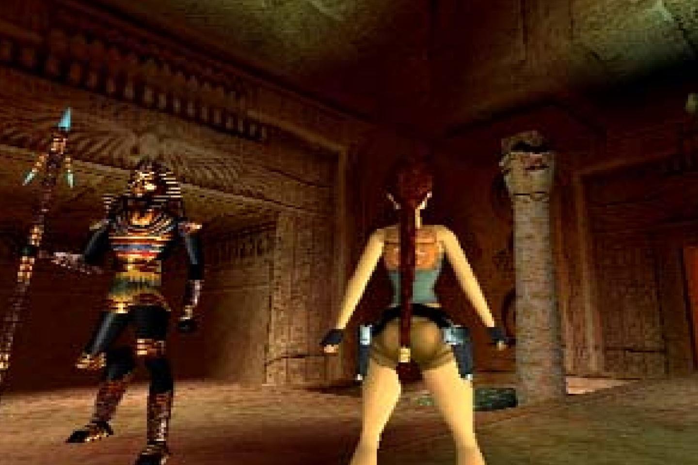 Lara standing near tomb guardian holding large spear and wearing colorful Egyptian print.